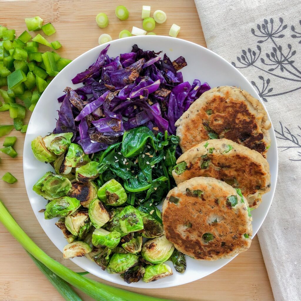 photo of salmon cakes with spinach, brussels sprouts, and sautéed cabbage