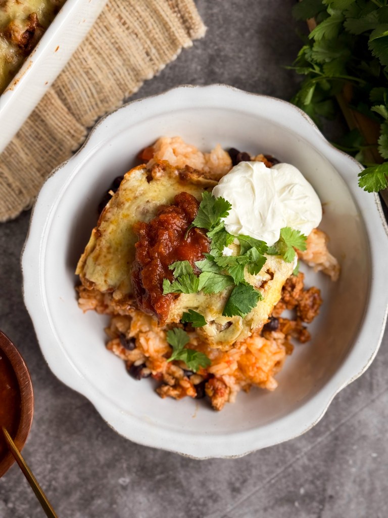 Healthy Taco Casserole in a bowl topped with sour cream, salsa, and cilantro. Also called a Healthy Taco Bake.
