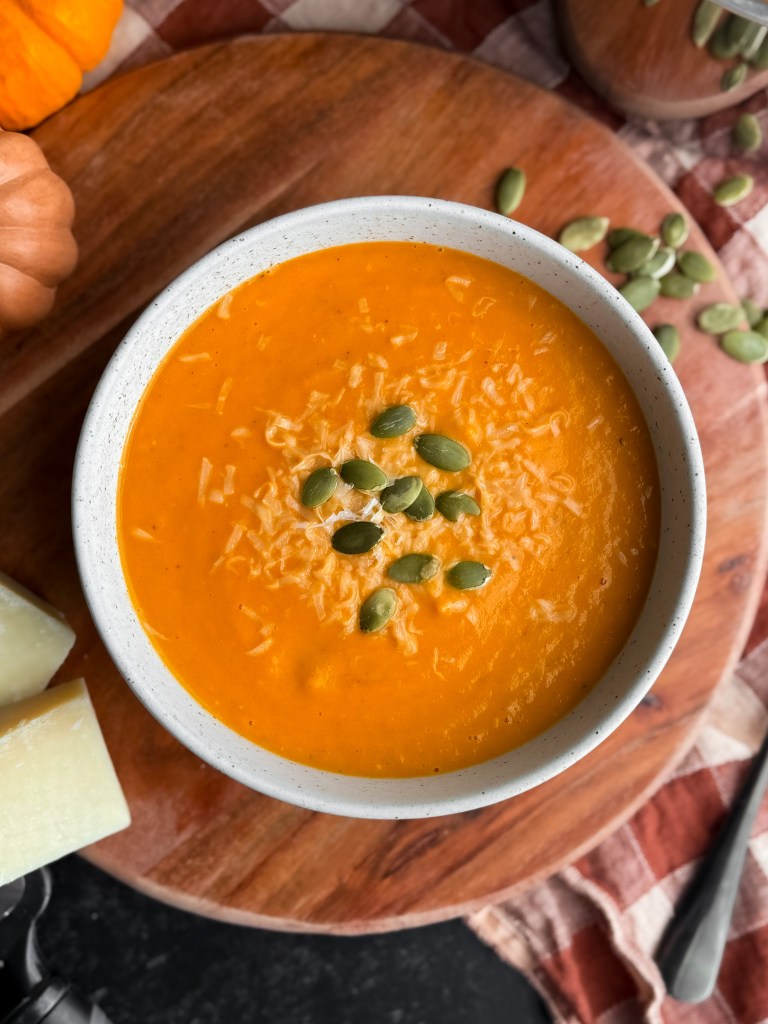 Pumpkin Tomato Soup topped with grated parmesan and pumpkin seeds