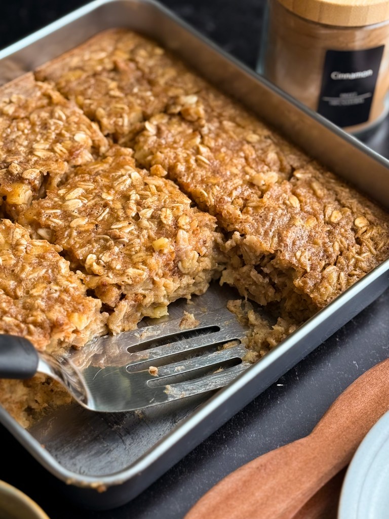 A metal spatula about to scoop up a fresh hot slice of Almond Butter Banana Baked Oatmeal