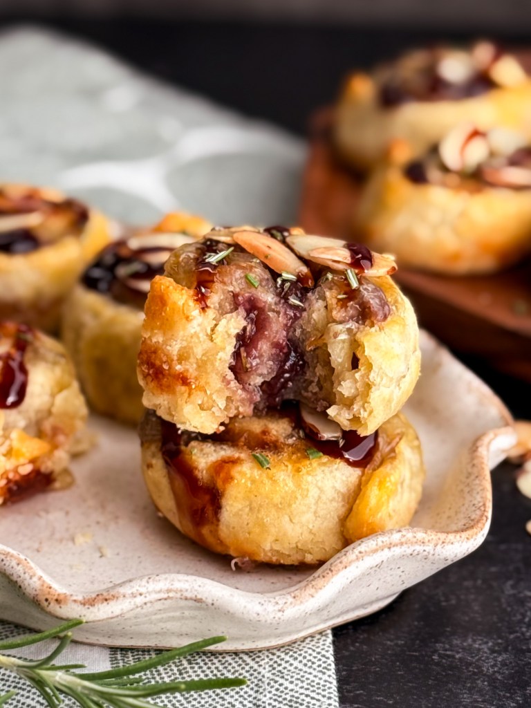 Fortunata Pastries - pie crust pastry stuffed with brie, jam, and rosemary and baked in the oven, then drizzle with balsamic glaze and topped with toasted almonds and chopped rosemary.