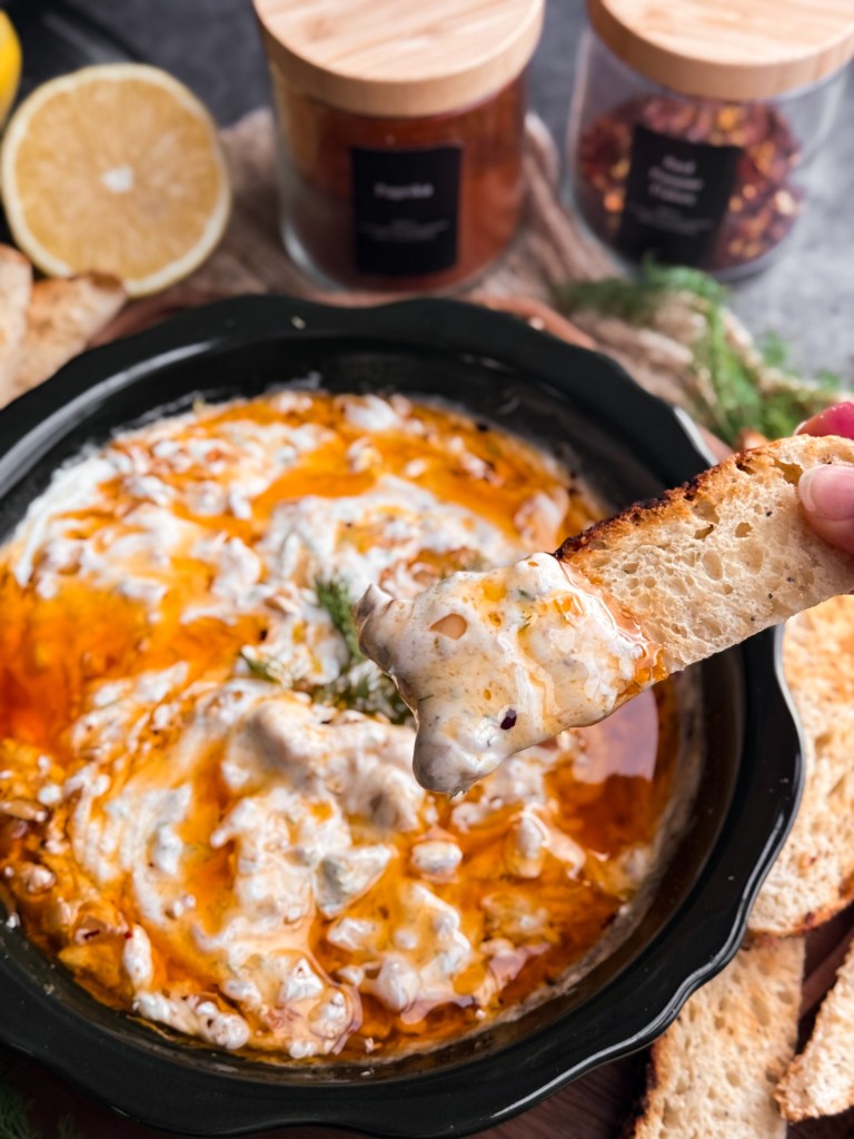 Toasted sourdough slice dipped into Zesty Yogurt Dip with a Chili Oil that has walnuts, shallots, garlic, and red pepper flakes. 
