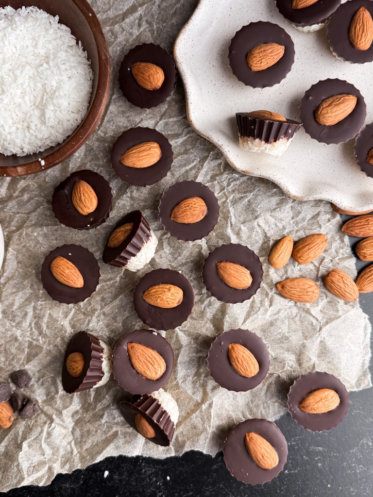 Healthy Almond Joy Cups that are low in sugar and scattered around on parchment paper. - aka healthy Almond Joys!